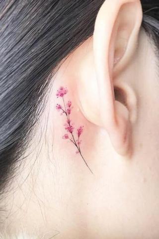 Minimalistyczny tatuaż kwiatek za uchem